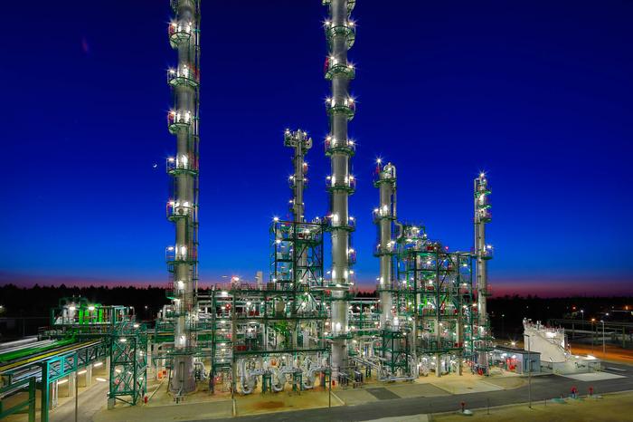 Große Industrieanlage mit beleuchteten Türmen bei Nacht